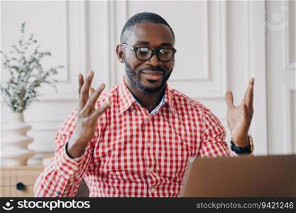 Ecstatic black man in glasses, reading laptop news, celebrates office success; a joyful African employee.