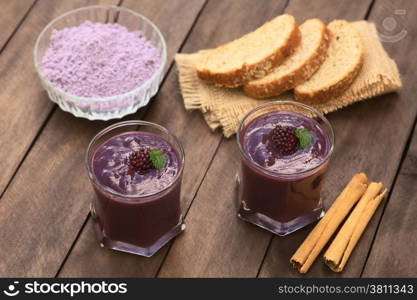 Ecuadorian traditional thick drink called Colada Morada, prepared by cooking purple corn flour and different fuits (for example strawberry, pineapple, naranjilla, grape, babaco, blackberry, etc) and seasoned with panela (cane sugar), cinnamon, allspice and cloves; accompanied by bread (Selective Focus, Focus on the blackberry on the left drink)