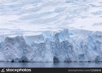 Edge of blue shimmering glacier tongue flows directly into the cold sea of the Antarctic
