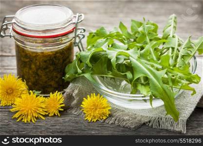 Edible dandelions and dandelion jam. Foraged edible dandelions flowers and greens with jar of dandelion preserve