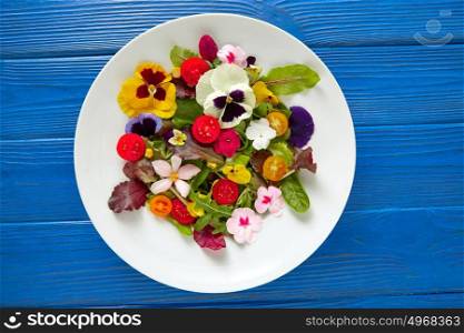 Edible flowers salad in a plate on blue wooden table
