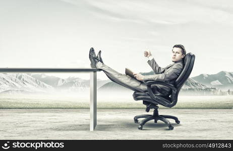 Education advantage. Young confident businessman sitting in chair with book in hands