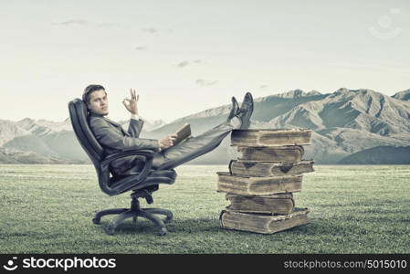 Education advantage. Young confident businessman sitting in chair with book in hands