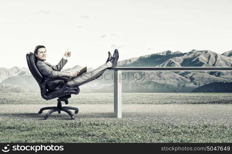 Education advantage. Young confident businessman sitting in chair with book in hands