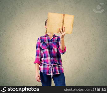 Education advantage. Young woman in casual hiding face behind reading