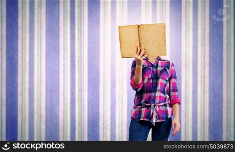 Education advantage. Young woman in casual hiding face behind reading