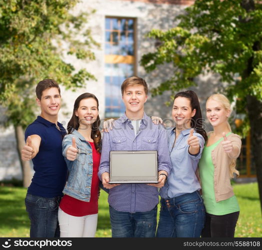 education, advertisement and new technology concept - smiling students with laptop computer blank screen showing thumbs up