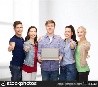 education, advertisement and new technology concept - smiling students with laptop computer blank screen showing thumbs up