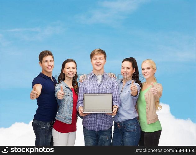 education, advertisement and new technology concept - smiling students with laptop computer blank screen showing thumbs up over blue sky background