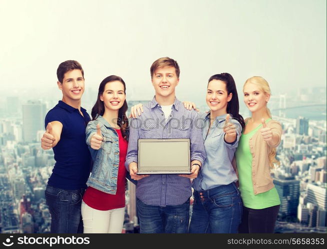 education, advertisement and new technology concept - smiling students with laptop computer blank screen showing thumbs up