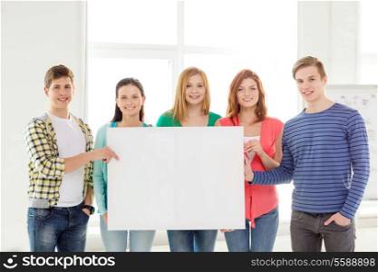 education, advertisement and school concept - group of smiling students at school holding white blank board