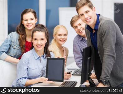 education, advertisement, techology and internet concept - group of smiling students with computer monitor and blank black tablet pc screen