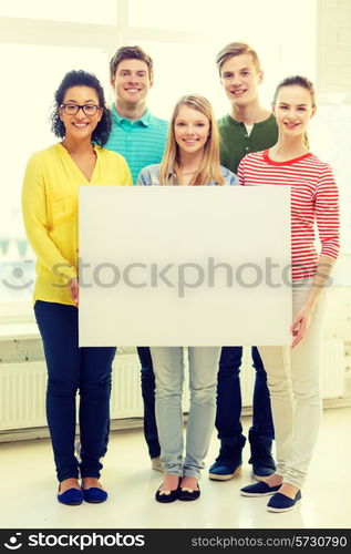 education, advertising and school concept - five smiling students with white blank board at school