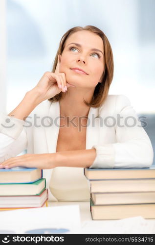 education and business concept - dreaming young businesswoman with many books indoors