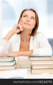education and business concept - dreaming young businesswoman with many books indoors