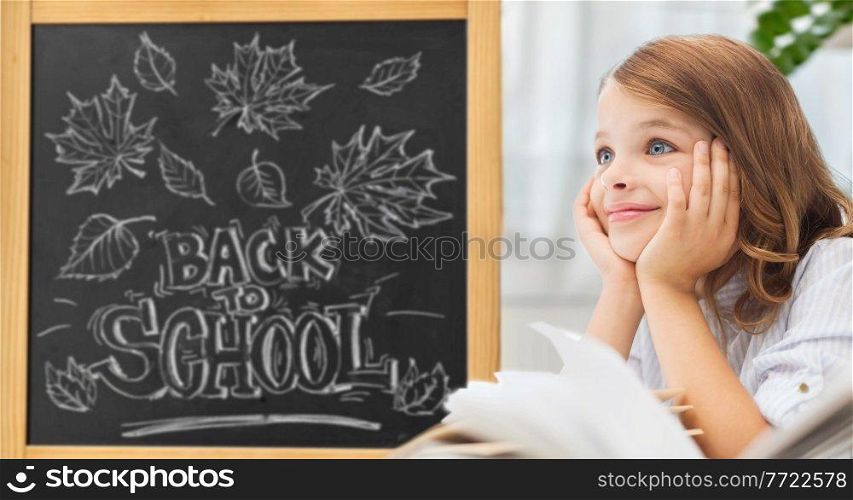 education and children concept - little student girl with books over chalk board with back to school lettering on background. student girl with books over school chalkboard