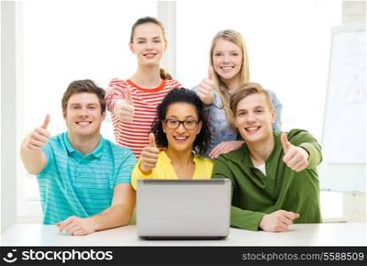 education and college concept - five smiling students with laptop at school showing thumbs up