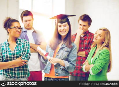 education and competition concept - girl in graduation cap with certificate and students. girl in graduation cap with certificate