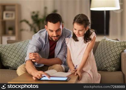 education and family concept - happy father and daughter with book and tablet computer doing homework together at home. father and daughter doing homework together