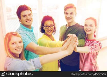 education and friendship concept - five smiling students giving high five at school. five smiling students giving high five at school