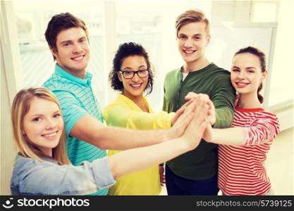 education and friendship concept - five smiling students giving high five at school