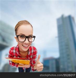 education and gesture concept - smiling student in black eyeglasses with folders showing thumbs up
