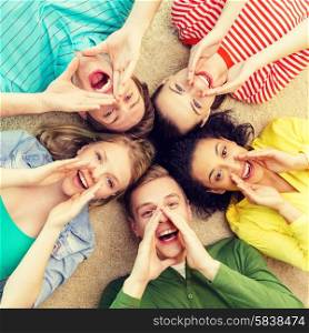 education and happiness concept - group of young smiling people lying down on floor in circle screaming and shouting