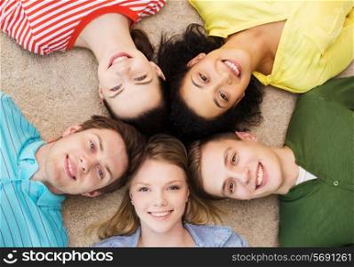 education and happiness concept - group of young smiling people lying down on floor in circle