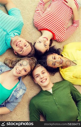 education and happiness concept - group of young smiling people lying down on floor in circle