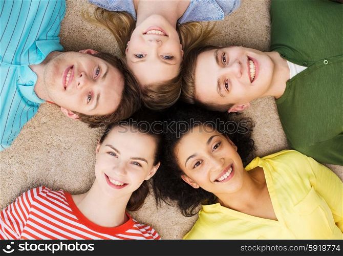 education and happiness concept - group of young smiling people lying down on floor in circle. group of smiling people lying down on floor