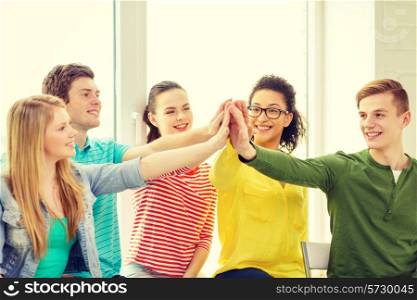 education and happiness concept - smiling students at school making high five gesture