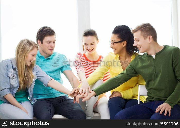 education and happiness concept - smiling students at school with hands on top of each