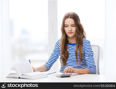education and home concept - concecntrated student girl with notebook, calculator and book
