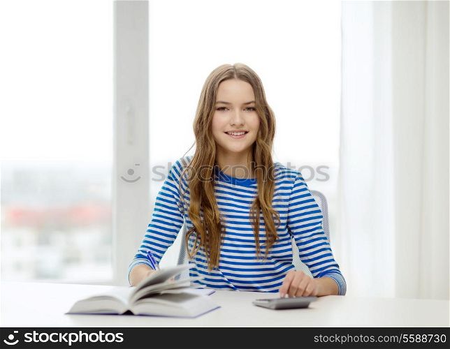 education and home concept - happy smiling student girl with notebook, calculator and book