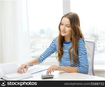 education and home concept - happy smiling student girl with notebook, calculator and book