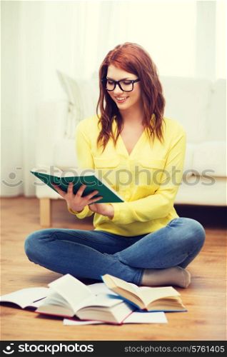 education and home concept - smiling student girl in eyeglasses reading books at home