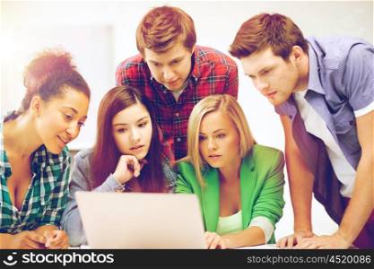 education and internet concept - group of international students looking at laptop at school. international students looking at laptop at school