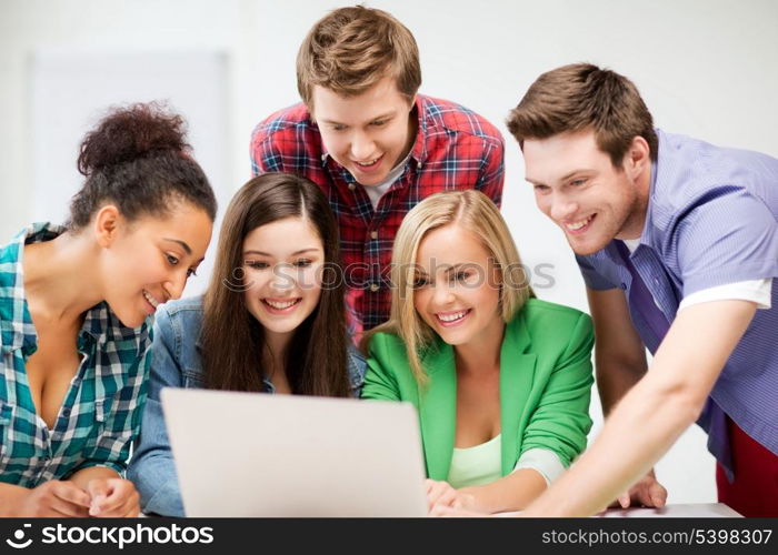 education and internet concept - group of international students looking at laptop at school