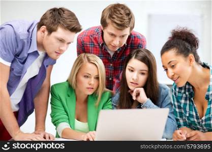 education and internet concept - group of international students looking at laptop at school