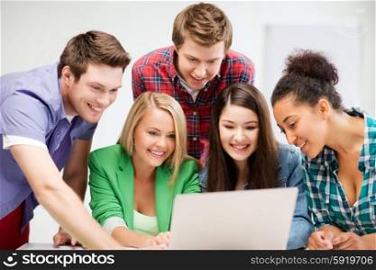 education and internet concept - group of international students looking at laptop at school. international students looking at laptop at school