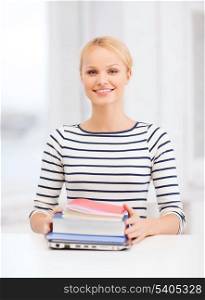 education and internet concept - smiling student girl with laptop, books and notebooks in college