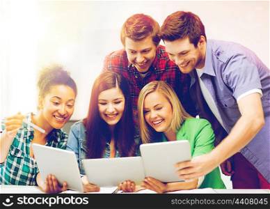 education and internet - smiling students looking at tablet pc in lecture at school. students looking at tablet pc in lecture at school