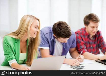 education and internet - smiling students writing test or exam in lecture at school. students writing test or exam in lecture at school