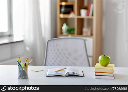 education and learning concept - books, apple and school supplies on table at home. books, apple and school supplies on table at home