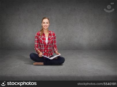 education and leisure concept - smiling young woman sitting on floor with book