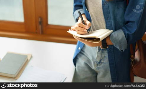 Education and literacy concept, College student girl thoughtful and taking note on notebook.