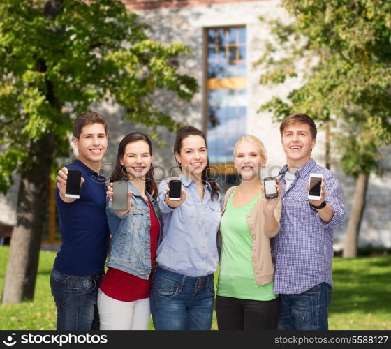 education and modern technology concept - smiling students showing blank smartphones screens