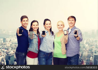 education and modern technology concept - smiling students showing blank smartphones screens