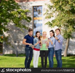 education and modern technology concept - smiling students using smartphones and tablet pc