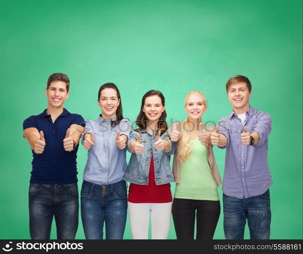 education and people concept - group of smiling students standing and showing thumbs up